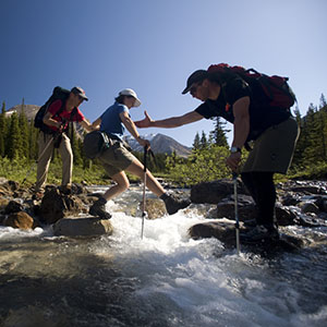 guides helping woman cross river in Canadian Rockies